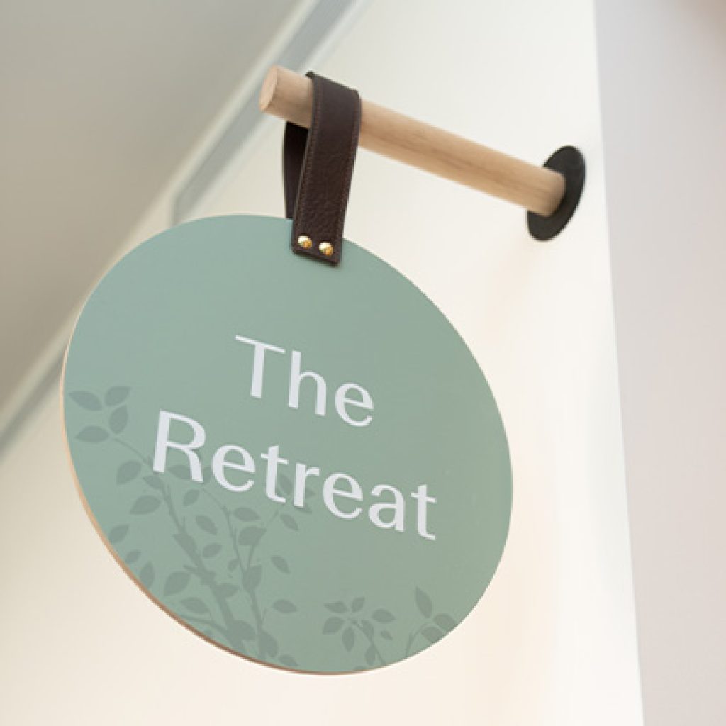 Signage hanging from a wooden peg. A circular sign says 'The Retreat'.