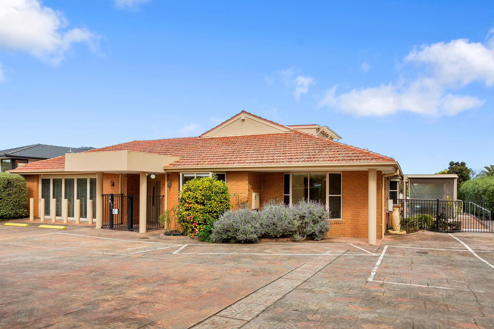 Single story orange bricked house with Brown tiled roof. Blue skies in the background