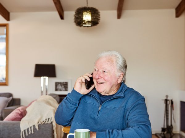 An older man on the phone, sitting at the dinner table.