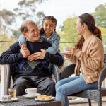 An older man having tea with a younger woman discussing his EOL pathway while a child giving him a hug.