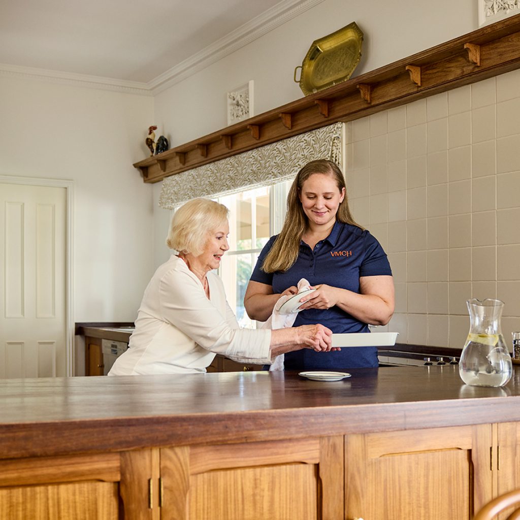 A support worker helping a Support at Home client clean the kitchen.