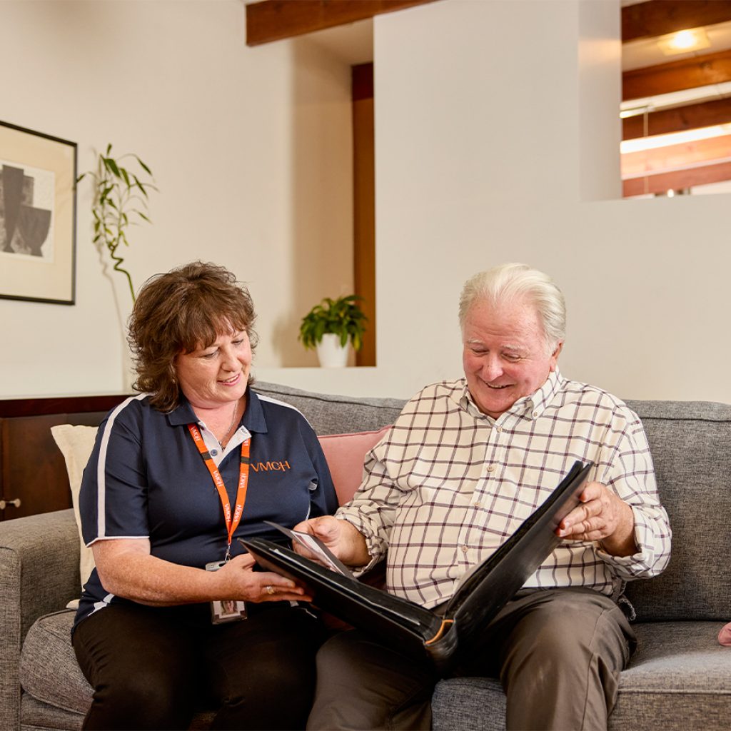 A support worker looking over paperwork for the Assistive Technology and Home Modifications (AT-HM) Scheme with a client in a living room.