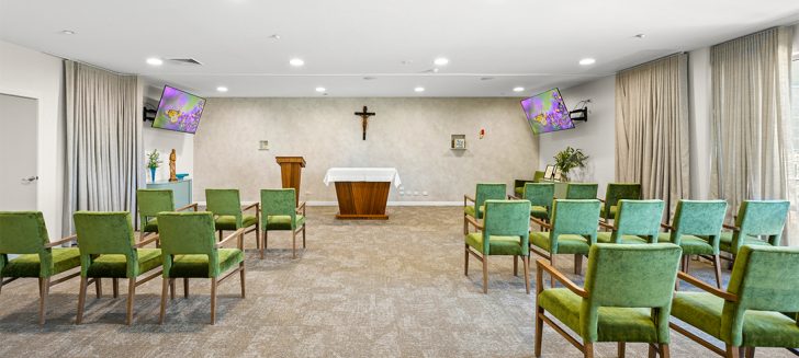 Chapel with rows of cushioned chairs.