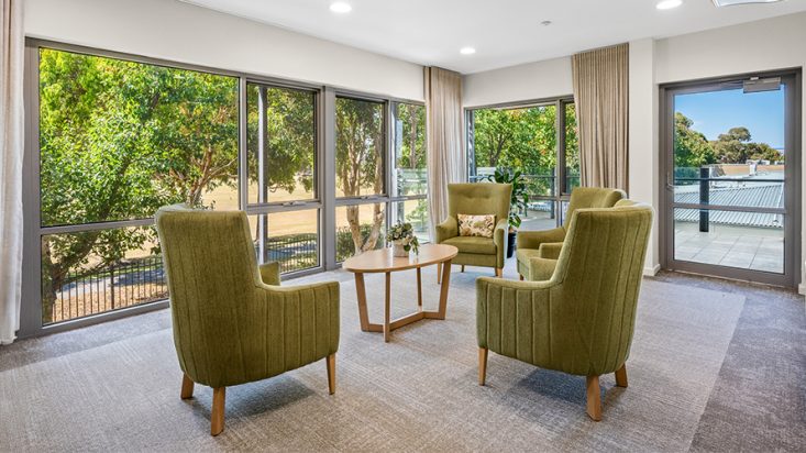 A lounge room with green armchairs at Corpus Christi Clayton Aged Care.