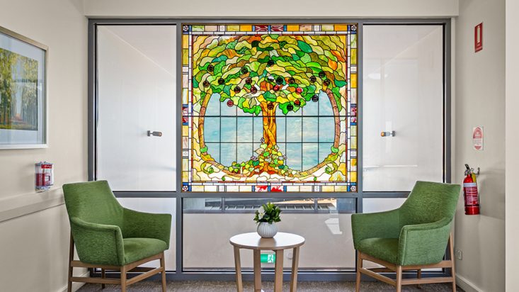 A bright glass mosaic of a tree at Corpus Christi Clayton Aged Care.