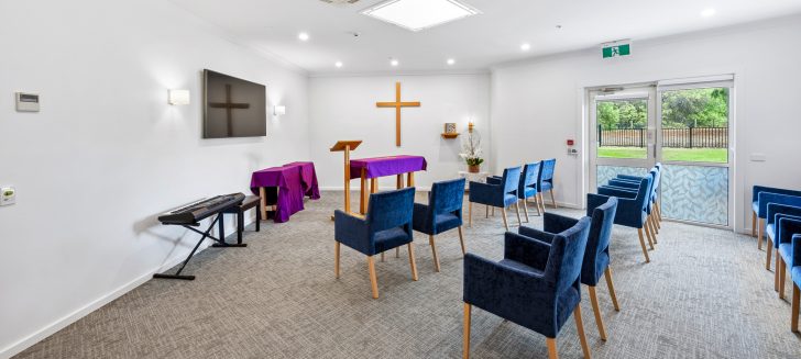 A chapel with blue armchairs arranged in rows.