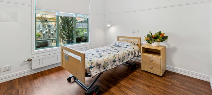A bedroom with hardwood floors and a wide window.