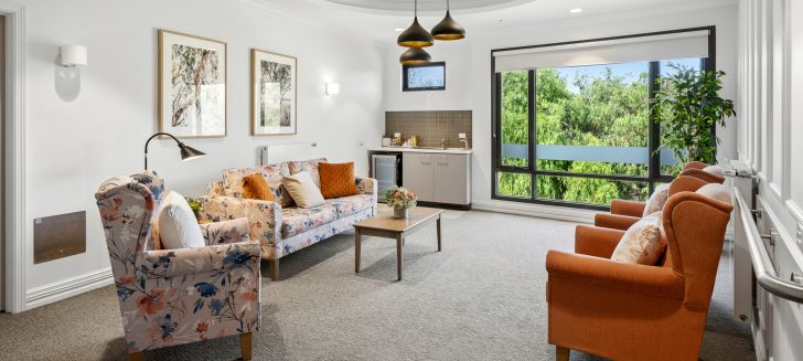 A living room with a small kitchenette and a statement light feature.