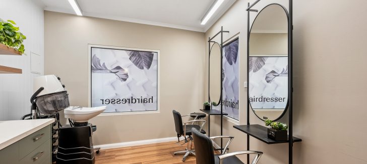 A serene salon with mirrors framed in black and green cabinetry.