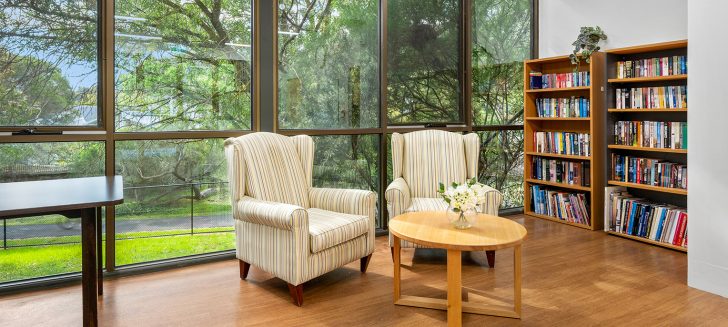 Two white armchairs with a bookshelf in the background.