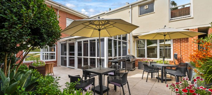A courtyard with several tables, chairs and umbrellas.