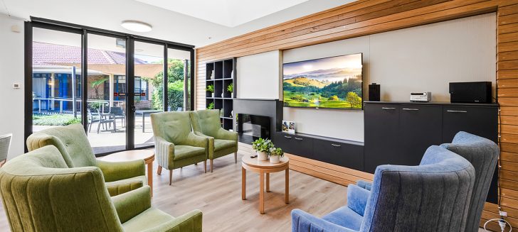 A lounge room with wide windows and green and blue chairs.
