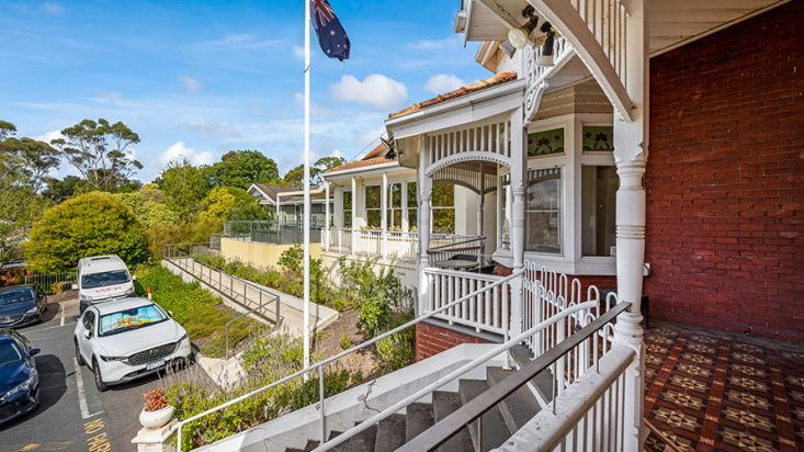 A balcony wrapping around a building with a white railing.