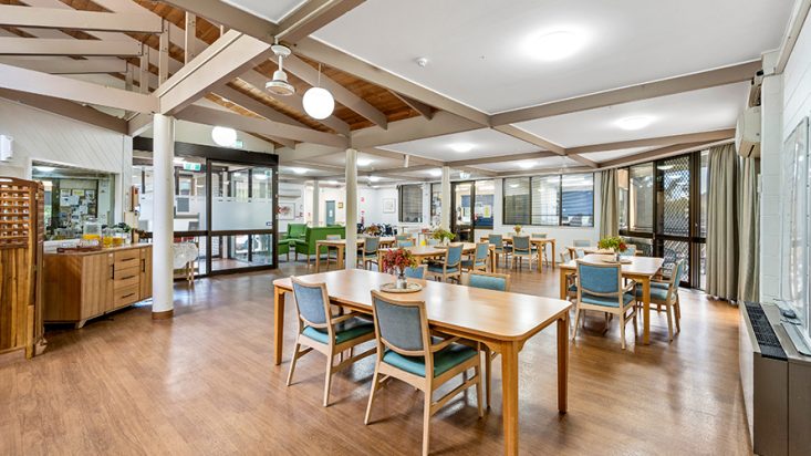 A dining room with blue chairs surrounding many tables.