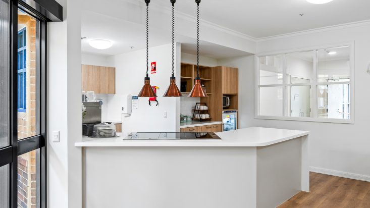 A kitchenette with heat lamps hanging over the white counter top at Berwick Aged Care.