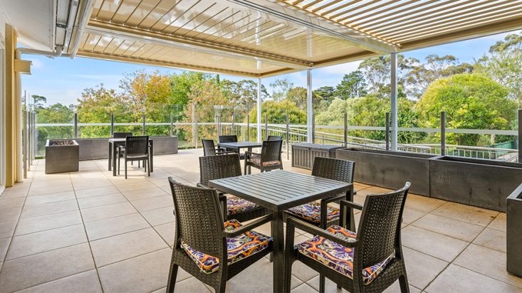 Deck furniture on a paved veranda overlooking greenery.