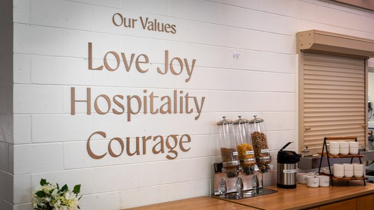 A bench with cereal dispensers and signage above attached to the wall.