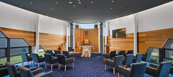 A chapel with a midnight blue carpet and dark ceiling.