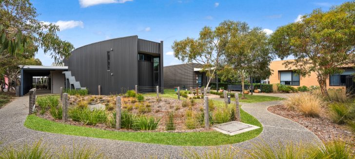 A garen path going around the aged care residence, passing bushes and grass.