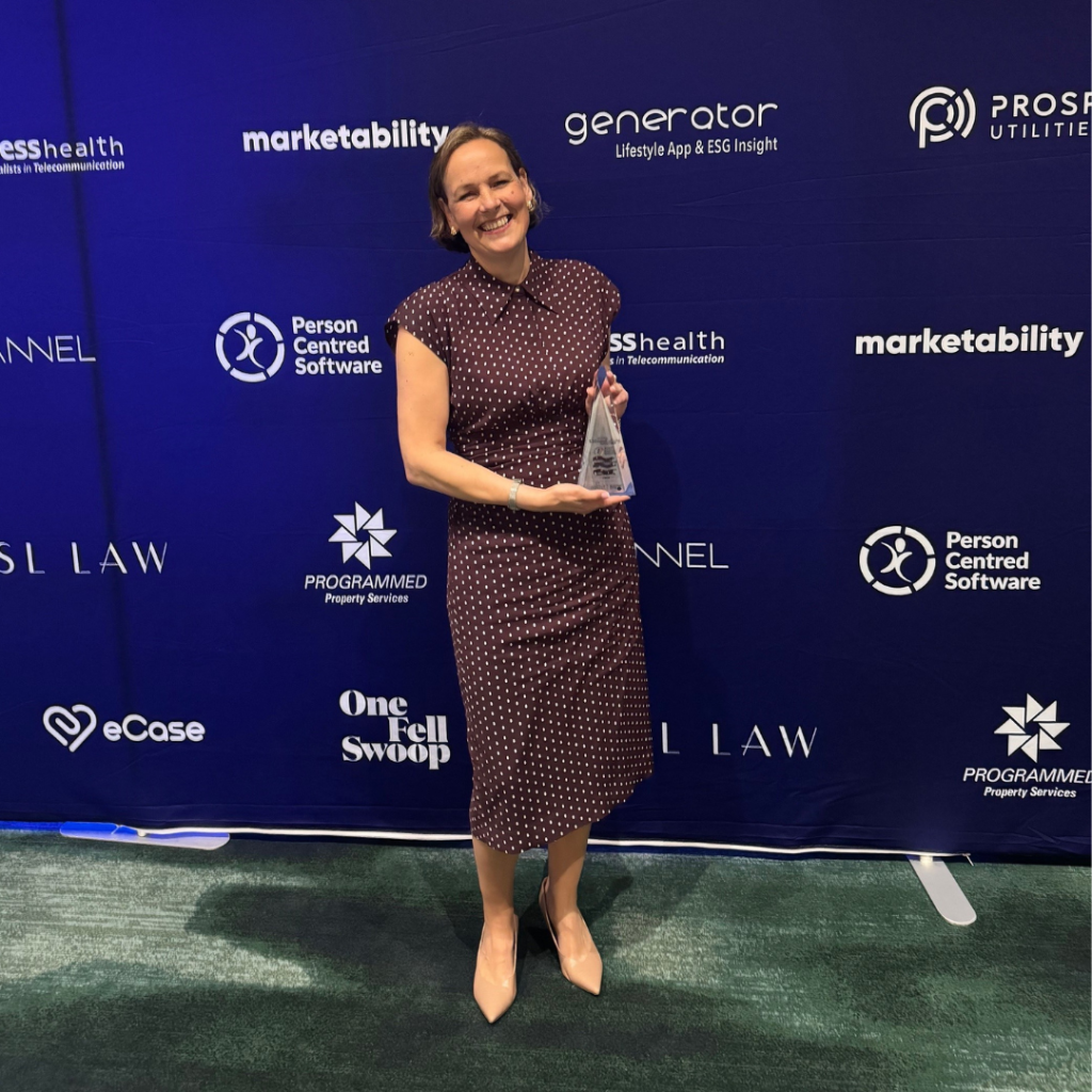 A woman stands holding a glass award