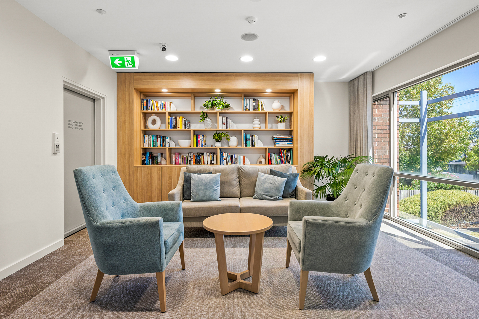 A sitting room with couches in front of an in-built, colourful book shelf.