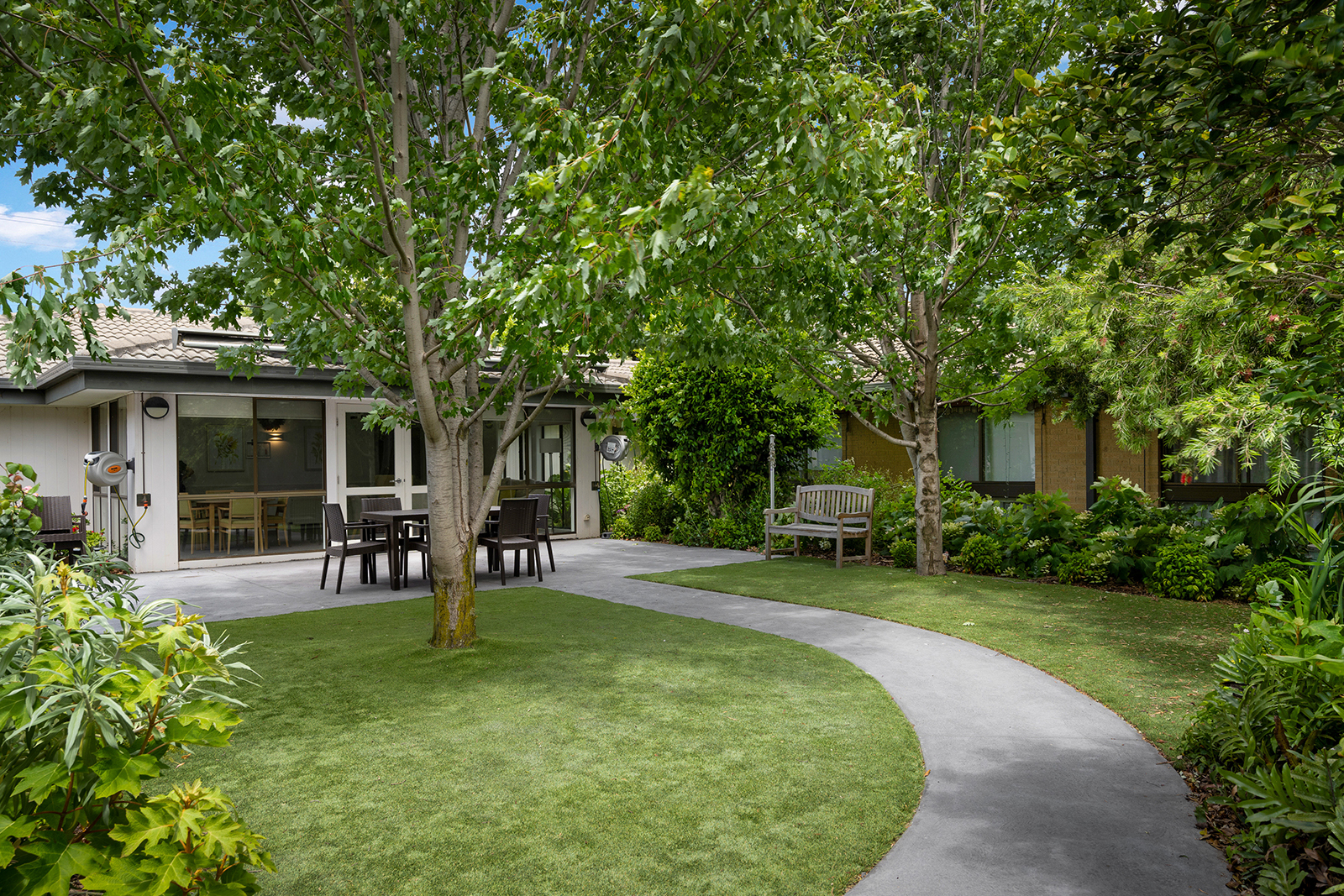A garden with a path cutting across the lawn, leading towards a building.