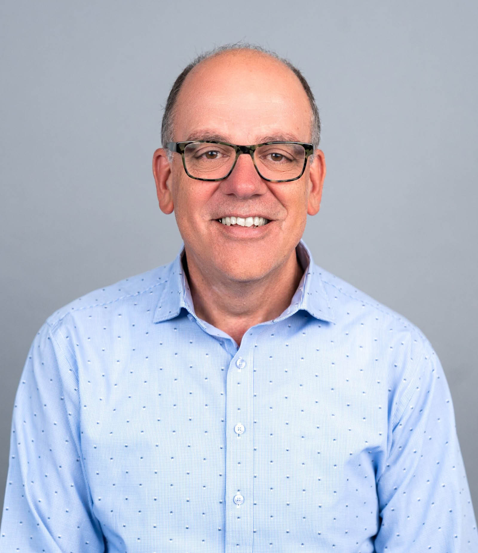 Man wearing a blue shirt and glasses, smiling