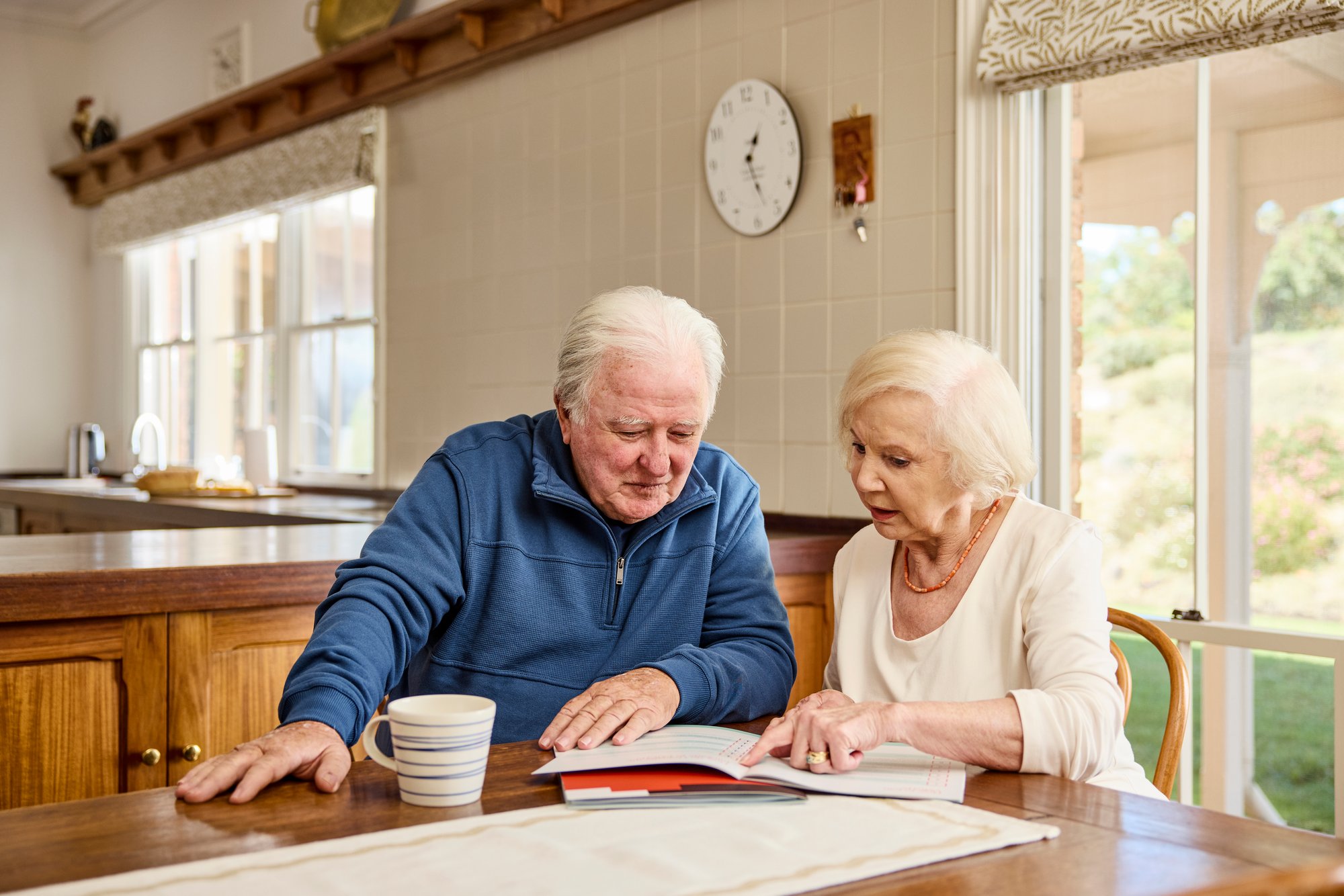 An older man and woman look at a book