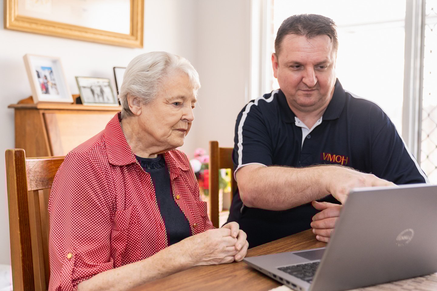 Older lady sitting with a male looking at a laptop together