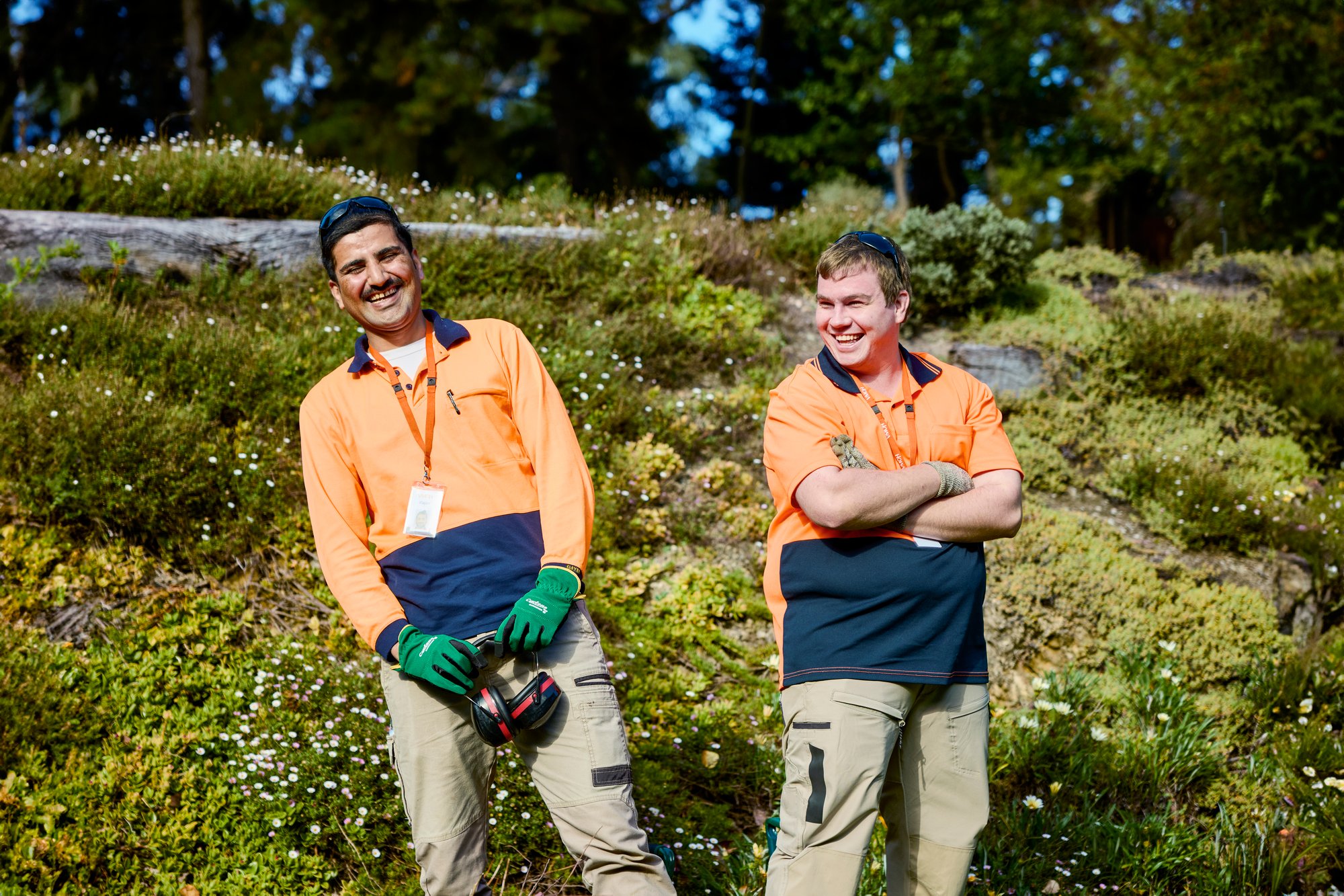 Two men standing in front of a garden wearing high-vis clothing