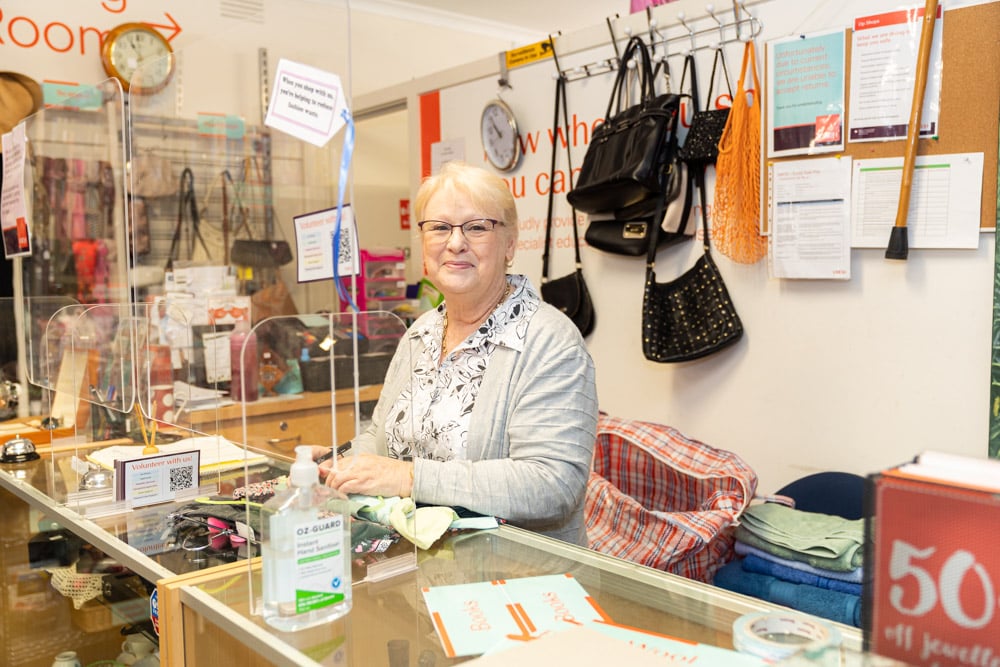 A woman stands behind a counter in an op shop
