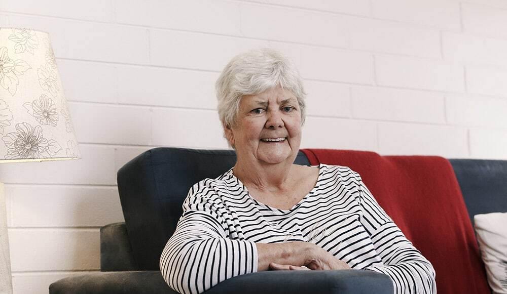 A women sitting on a couch with tears in her eyes.