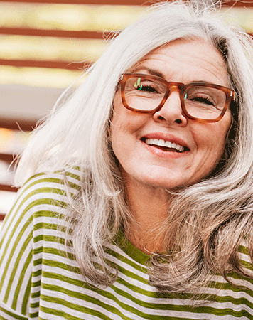Woman smiling with mouth open, wearing brown glasses