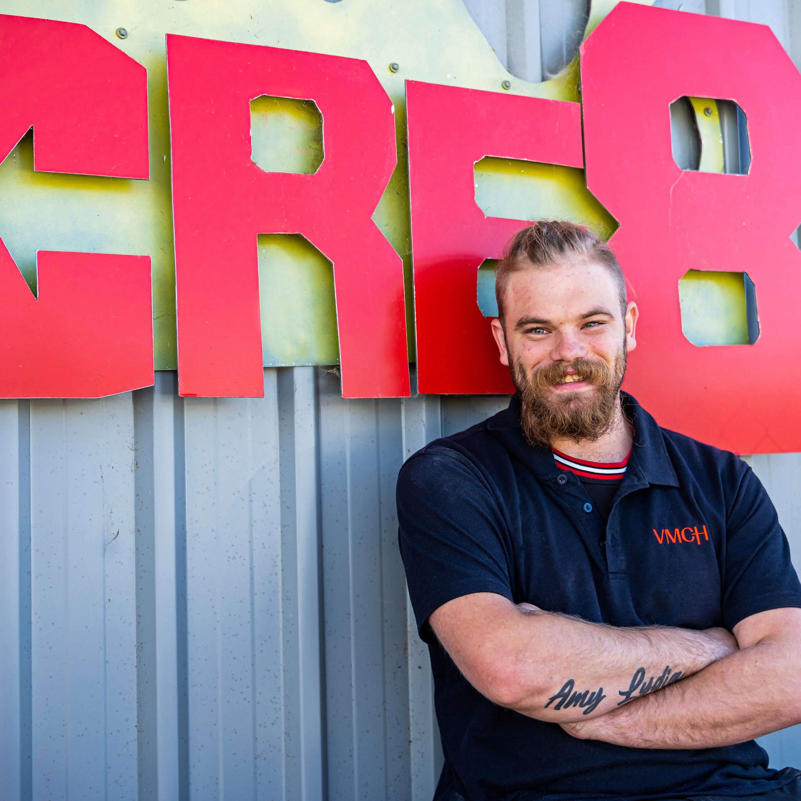 Male standing infront of the Cre8 sign, smiling